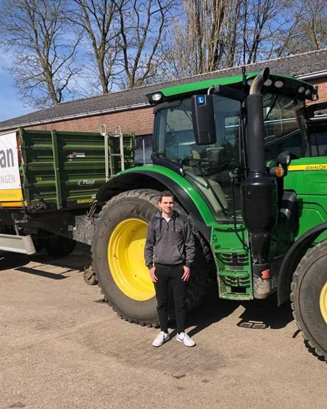 Geslaagde cursist naast een groene lestrekker met aanhangwagen van Kees de Vaan