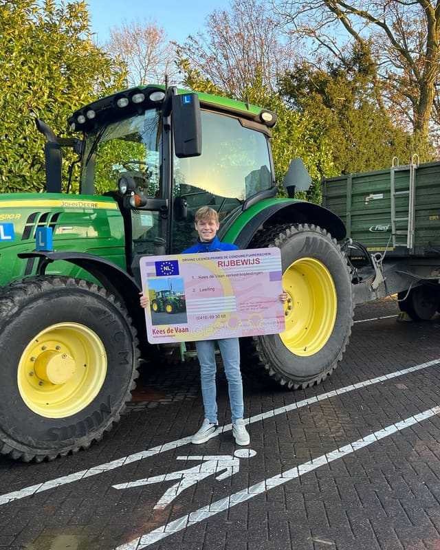 Geslaagd voor het trekkerrijbewijs: cursist met rijbewijsbord voor een groene lestrekker op het parkeervak