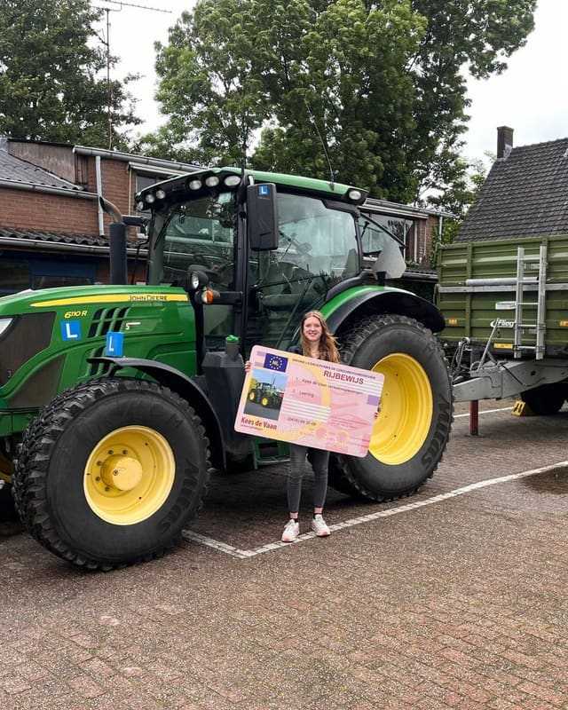 Geslaagde cursist met rijbewijsbord voor een groene lestrekker en kipper