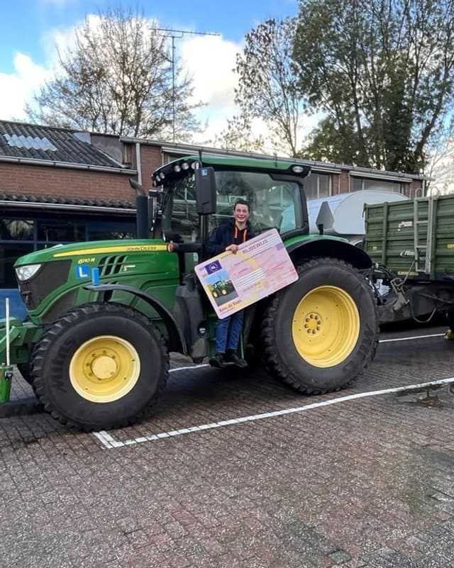 Geslaagd voor het trekkerrijbewijs: cursist met rijbewijsbord in de deur van de lestrekker