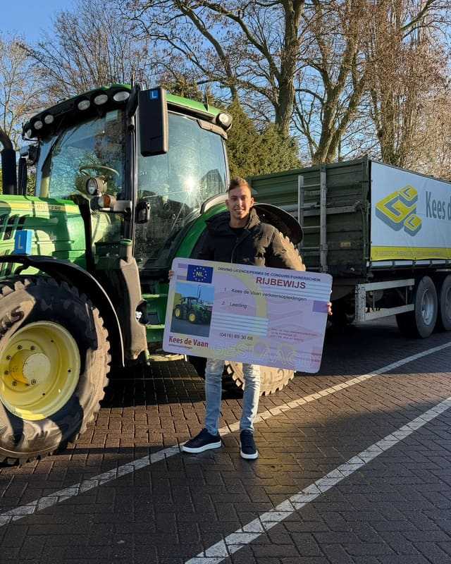 Geslaagde cursist met rijbewijsbord naast een groene lestrekker met kipper en L-bord