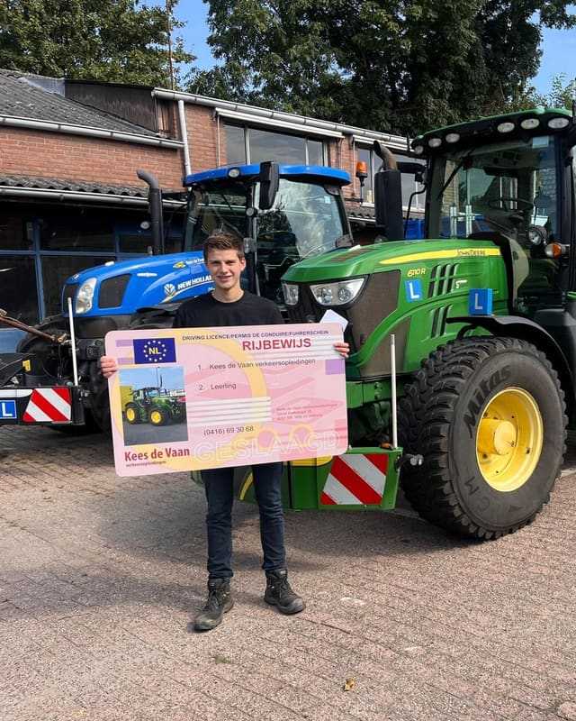 Geslaagd voor het T-rijbewijs: cursist met rijbewijsbord tussen een blauwe en een groene lestrekker