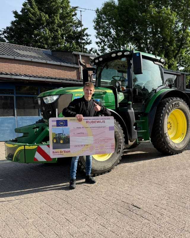 Geslaagd voor het T-rijbewijs: cursist met rijbewijsbord voor een groene lestrekker naast het lesgebouw